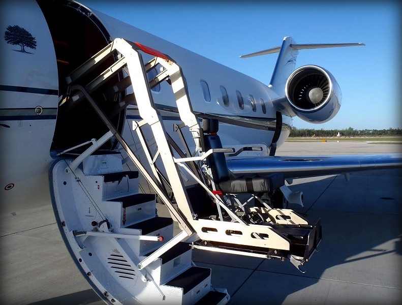 Hydraulic wheelchair lift raising a passenger to a private jet cabin door
